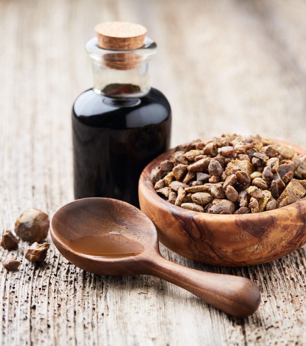 Propolis granules with tincture on wooden background